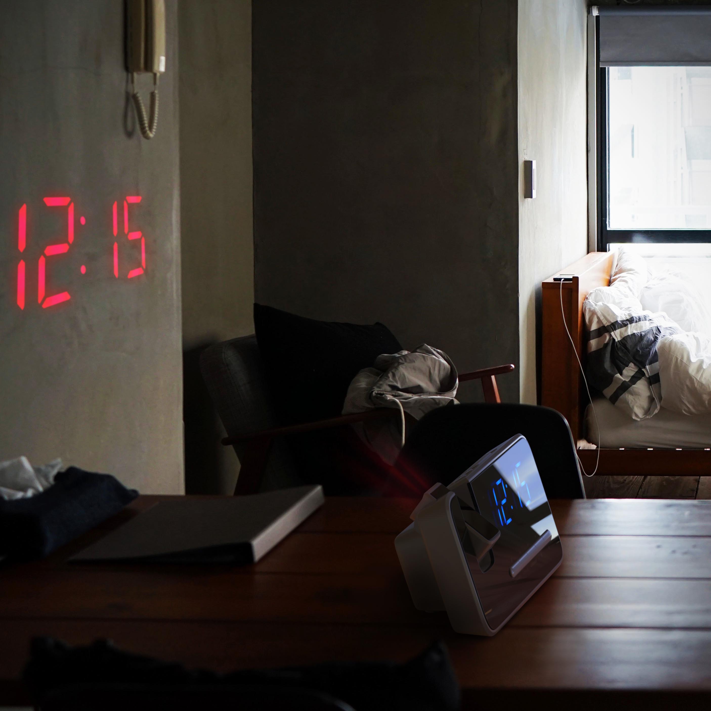 Brandson Wecker mit Projektionsfunktion, weißes Gehäuse, digitales Display zeigt die Uhrzeit in roter Schrift an, auf einem Tisch in einem Schlafzimmer.