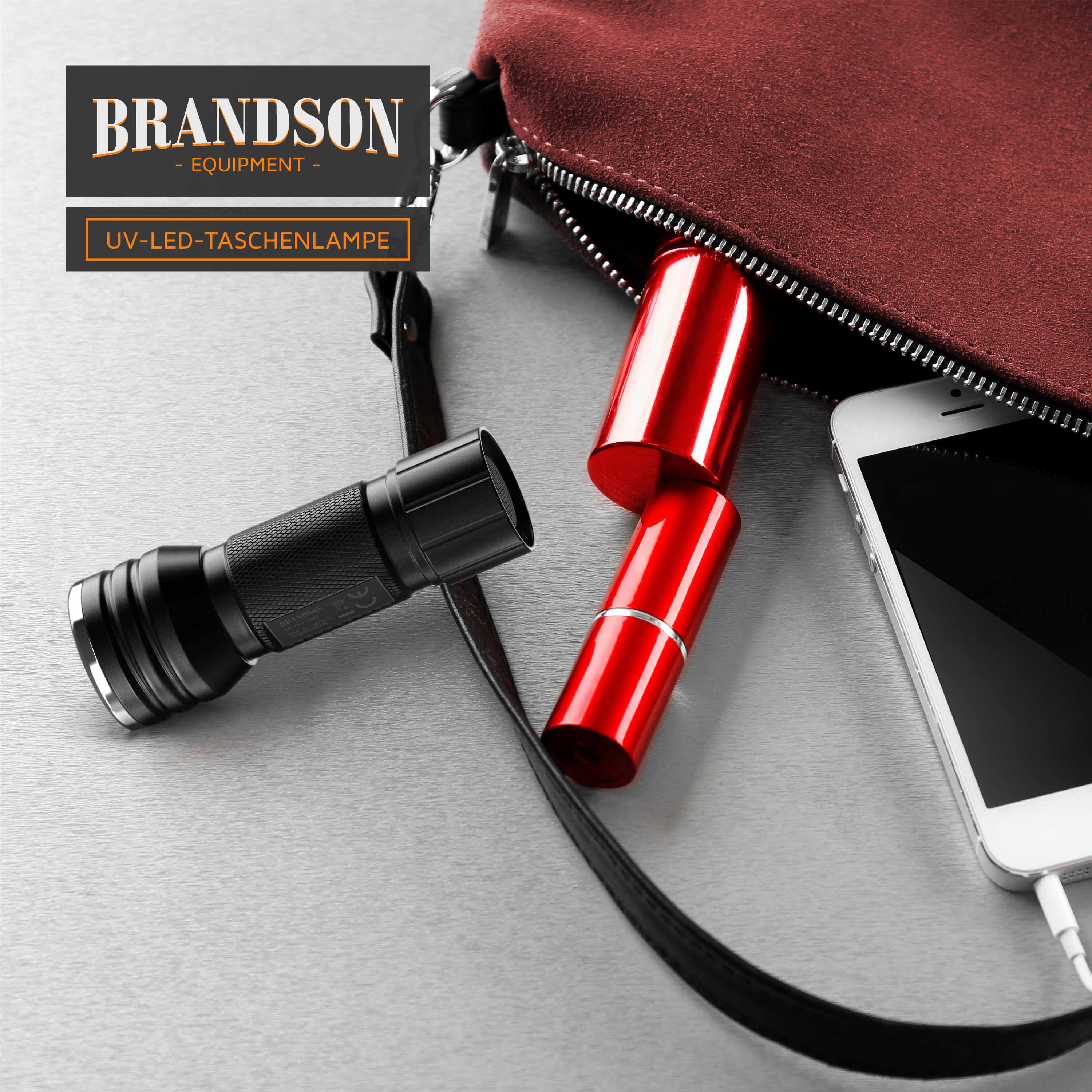 Brandson UV-LED-Taschenlampe in Schwarz neben einem roten Objekt in einer Tasche, mit einem Smartphone im Hintergrund.